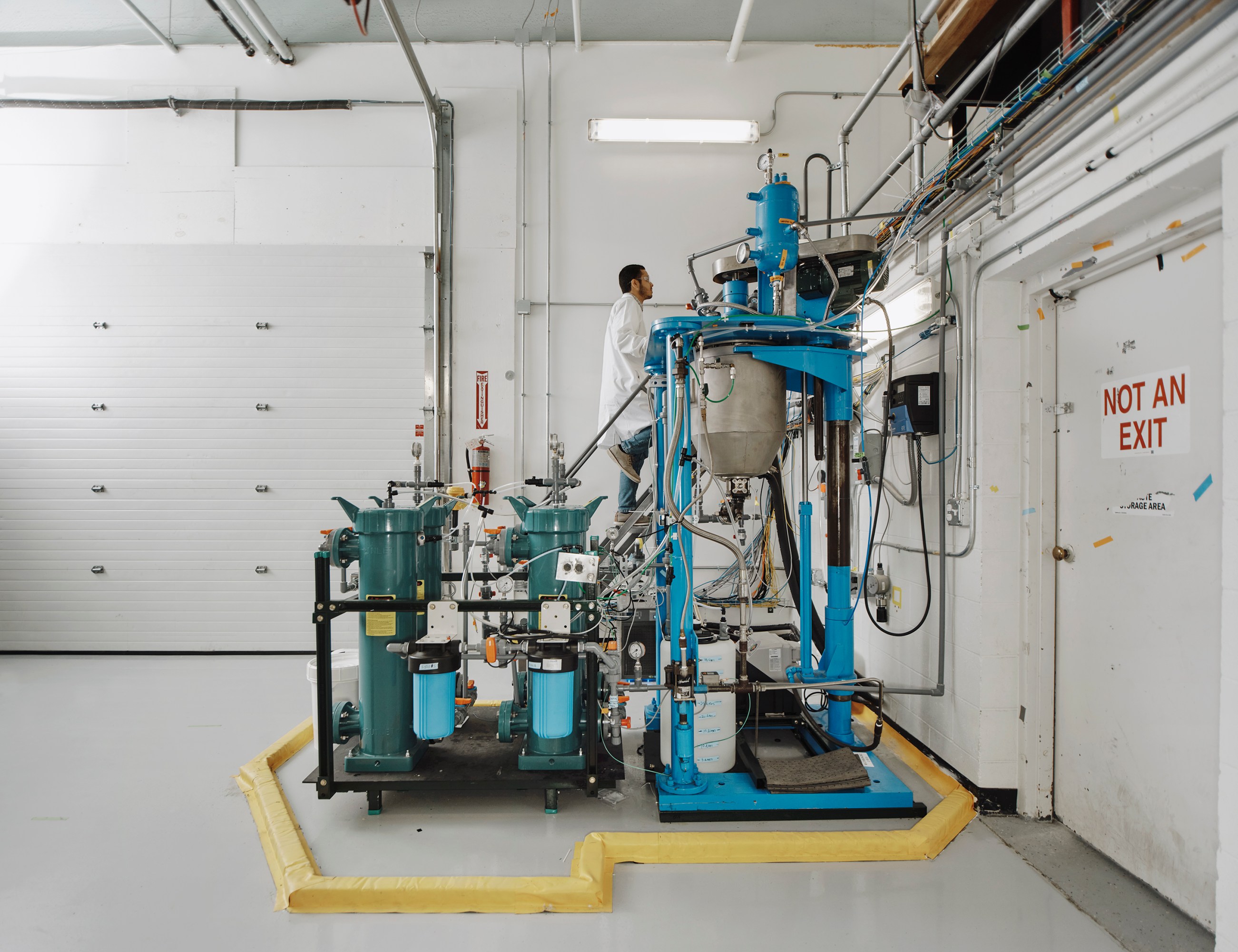 A man in a white coat is seen eyeing factory equipment.